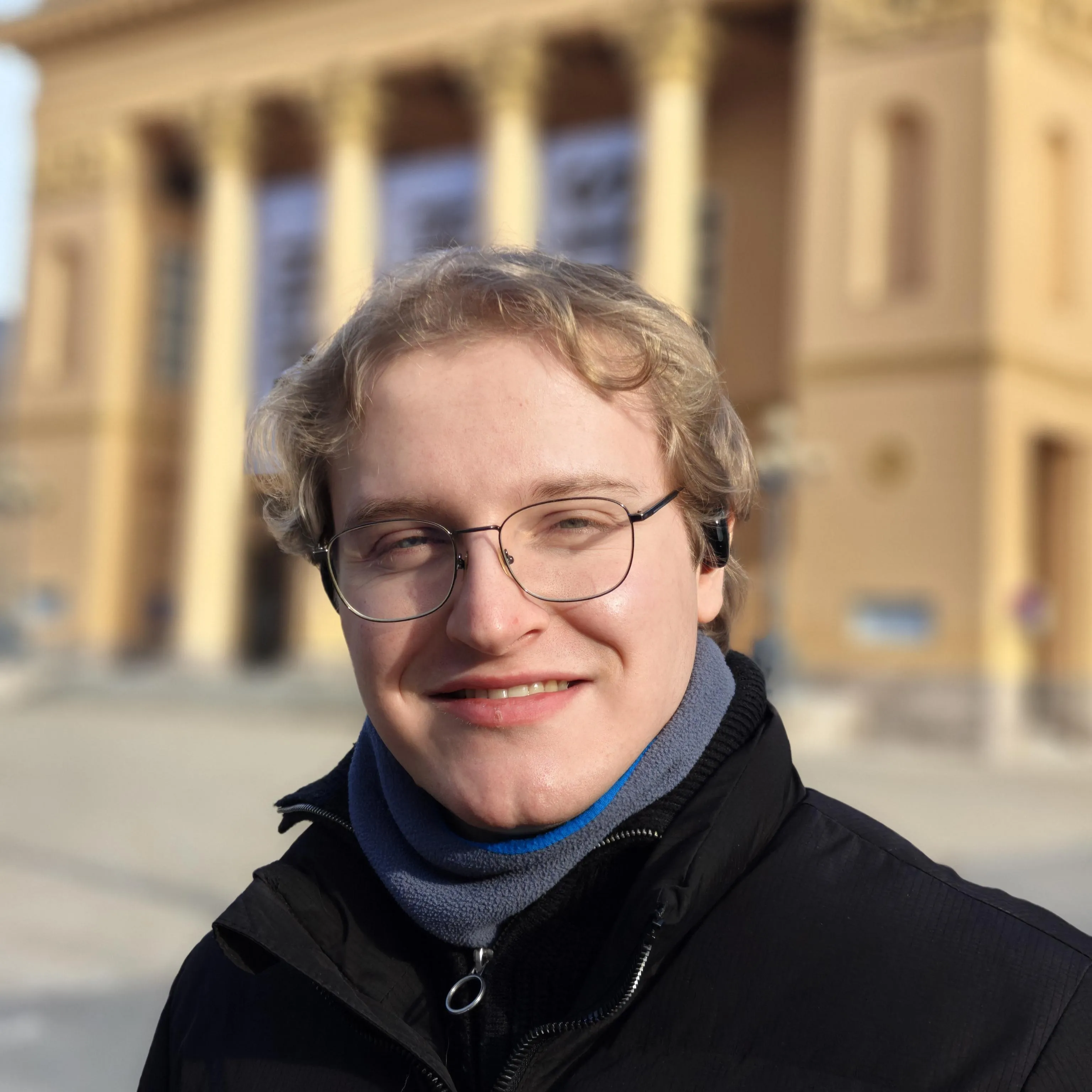 Ein gut aussehender, blonder, junger Mann, der nachdenklich in die Ferne blickt und einen schwarzen Pullover trägt